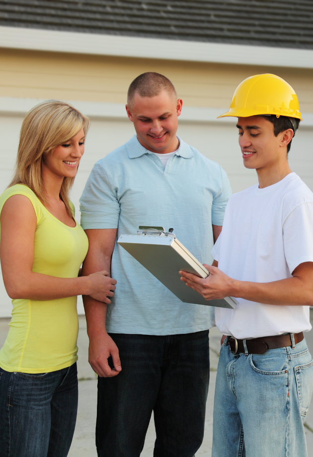 a contactor in a hard hat going over details with two home owners in their drive way